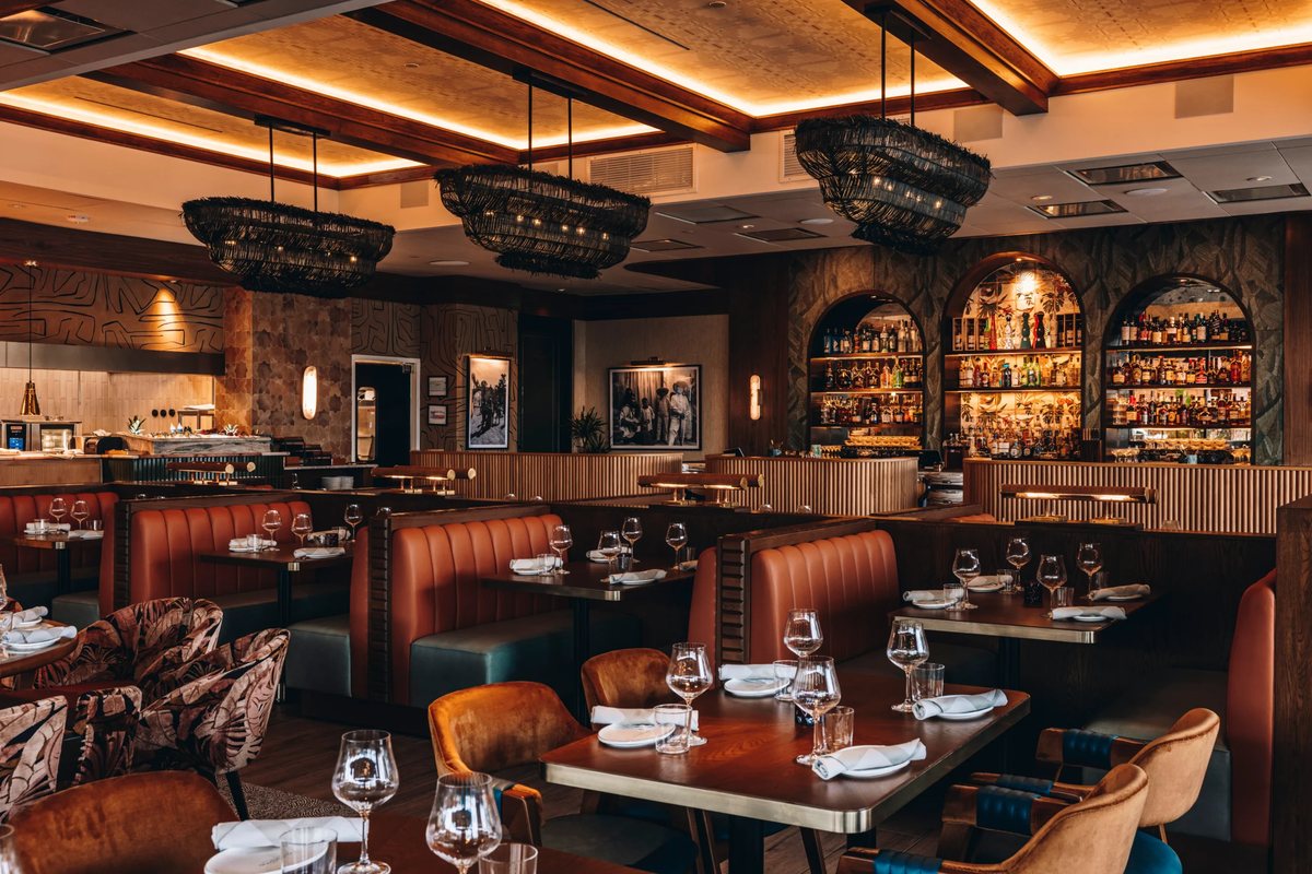 The dining room at Maroma with warm lighting, woven lanterns and the bar